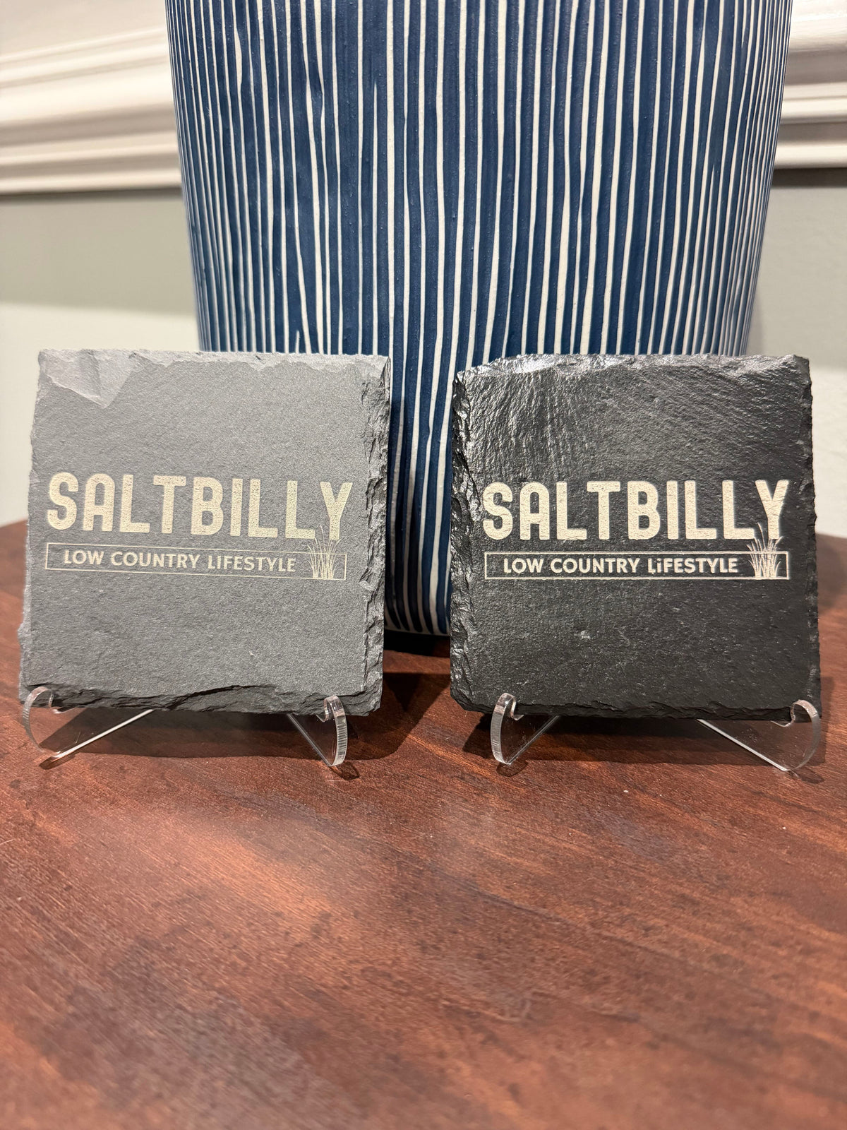 Raw and sealed slate coasters side by side, both engraved with the Saltbilly logo, showing the difference between the two finishes
