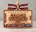Wooden football field shaker ornament with a coach's name, team name, and year, filled with football beads in school colors