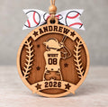 Round layered wood baseball ornament with a batter in a helmet, personalized with Andrew, West, number 08, and 2026, tied with a white baseball ribbon