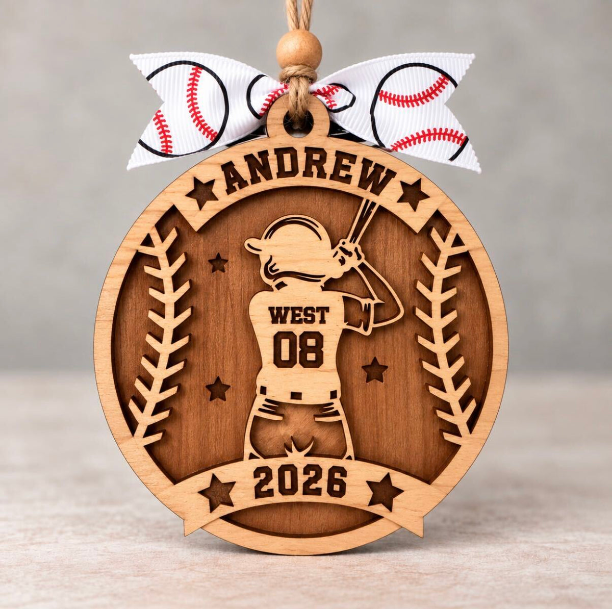 Round layered wood baseball ornament with a batter in a helmet, personalized with Andrew, West, number 08, and 2026, tied with a white baseball ribbon