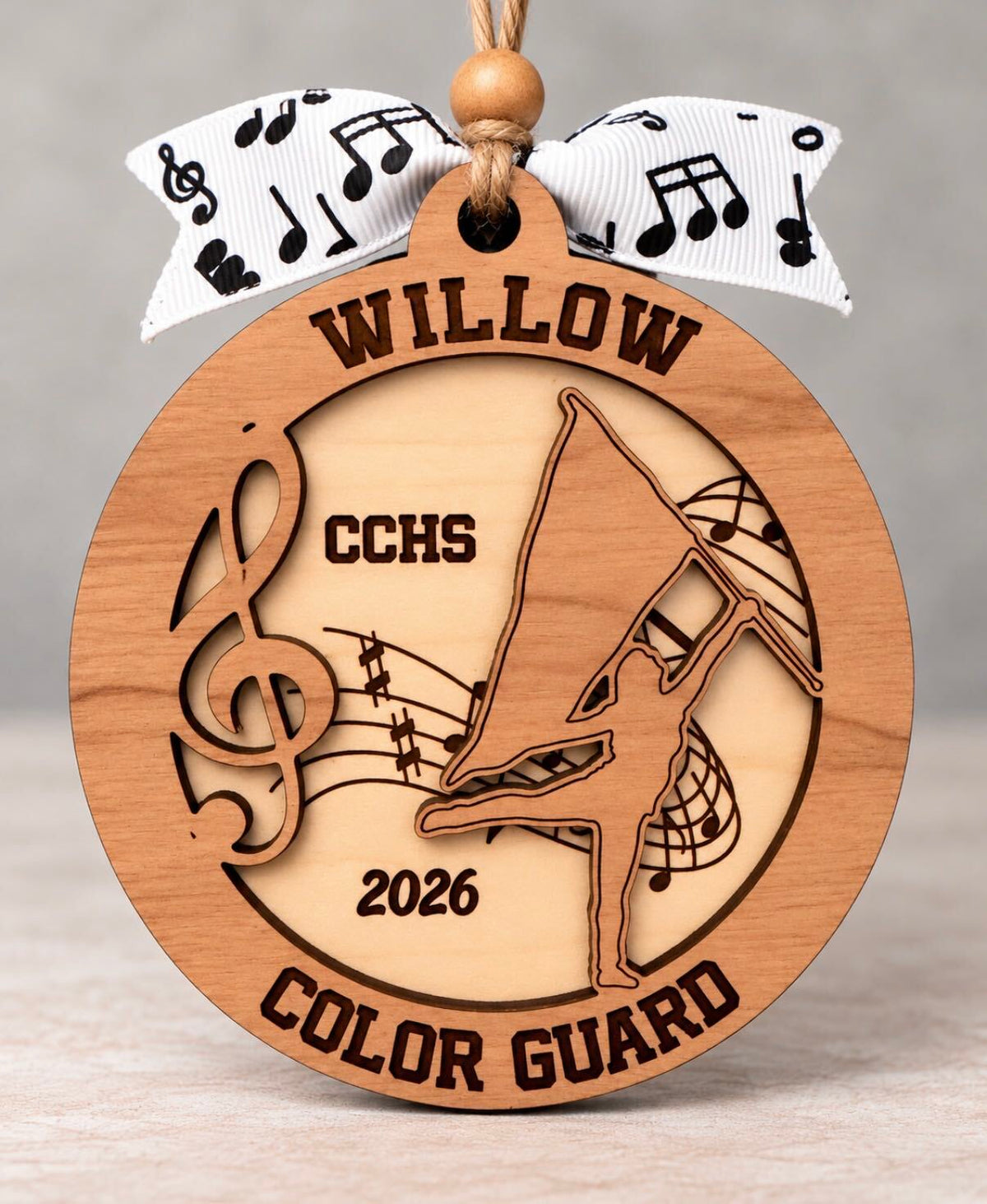 Round layered wood color guard ornament with a flag spinner and music notes, name, school, and year, tied with a music note ribbon