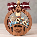 Round wooden football shaker ornament with a helmet, striped jersey, goal post, and pennant, filled with blue and white beads and mini footballs, personalized with Jason, Wildcats, and 2026
